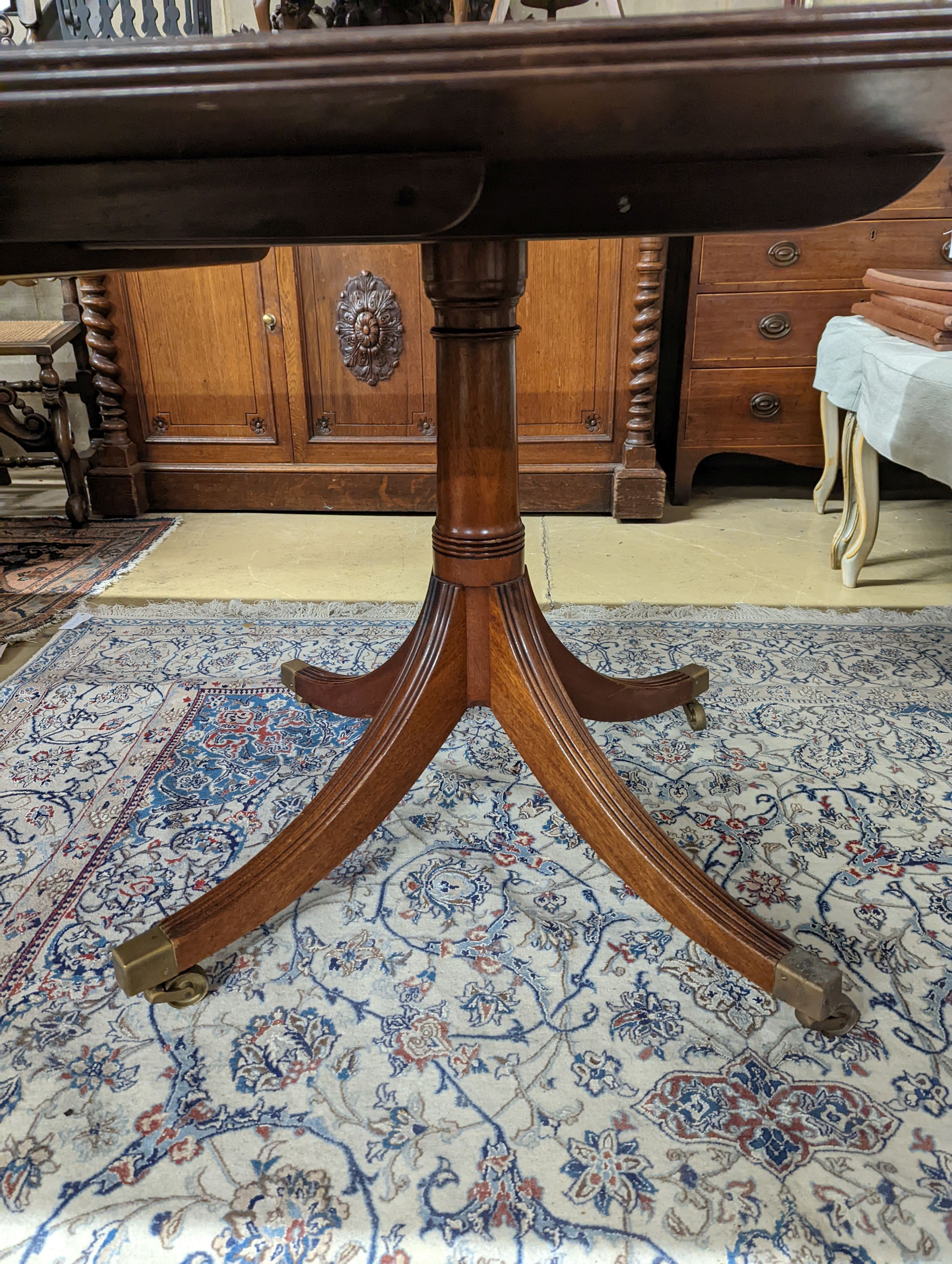 A reproduction George III style mahogany twin pillar extending dining table, two spare leaves, length 244cm extended, width 107cm, height 73cm